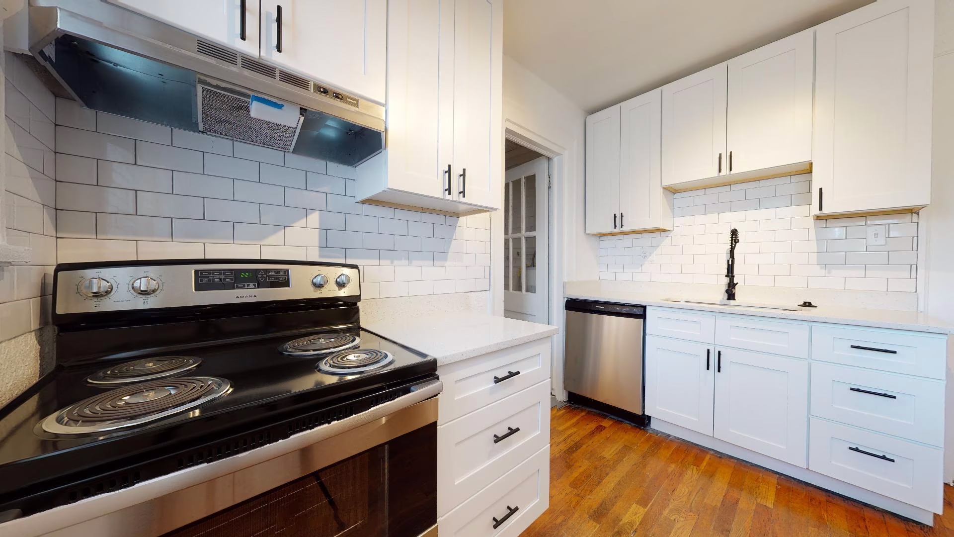 Kitchen with black electric stove and white cabinets at Candler Commons, located in Decatur, Georgia
